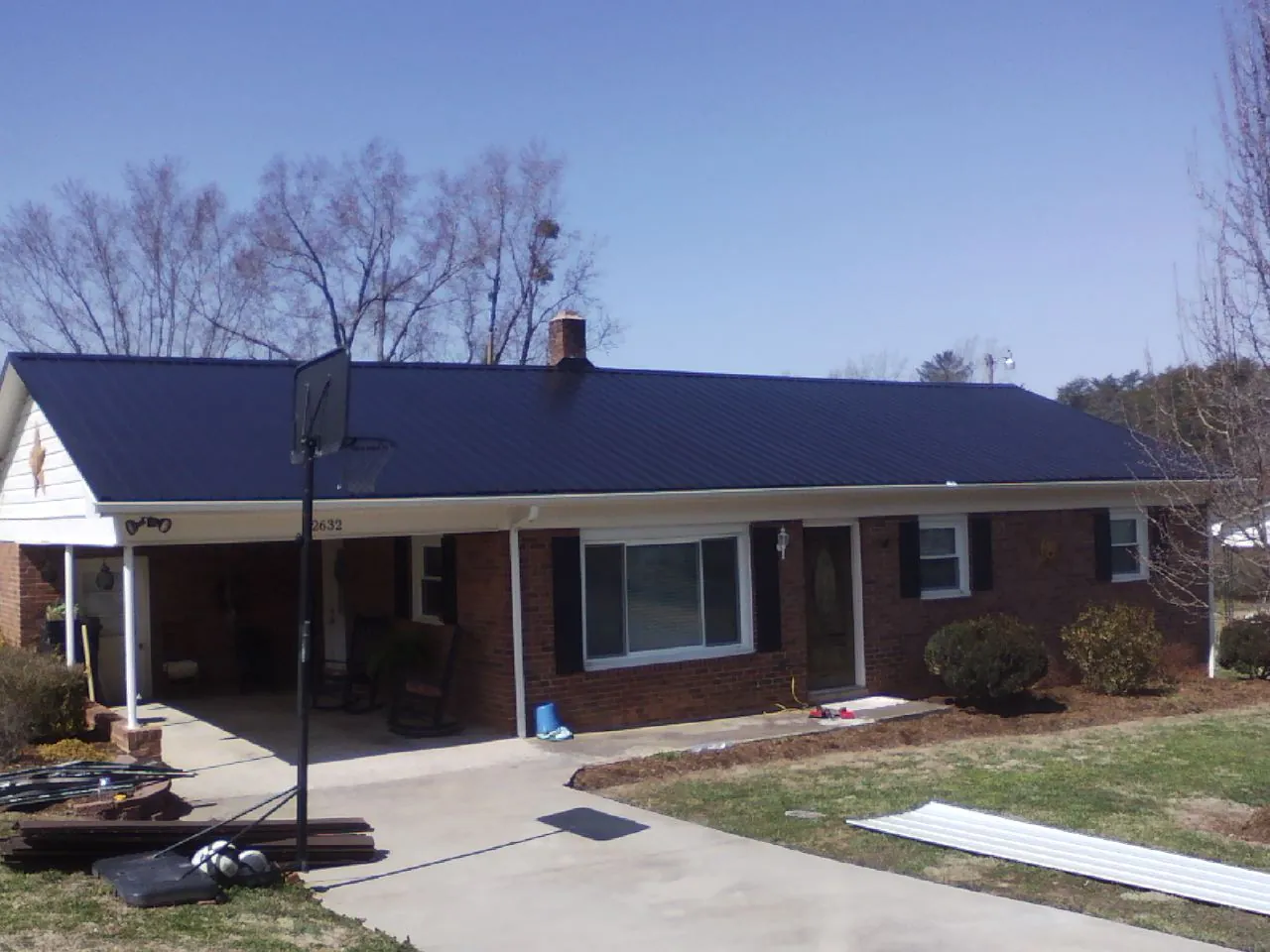 Finished dark blue metal roof on a brick ranch with a carport in Glenfield