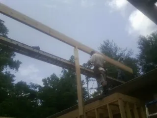 Carpenter setting a ridge beam over a new addition frame — Ice Dam Removal by Roofing Brothers in Glenfield