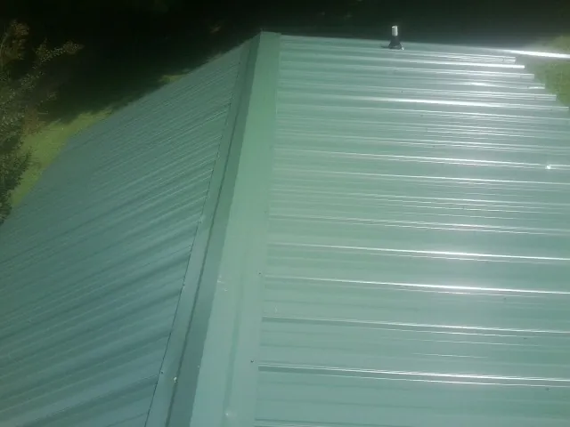 New green metal panels meeting at the ridge of a roof — Flat Roof Repair work by our crew in Glenfield