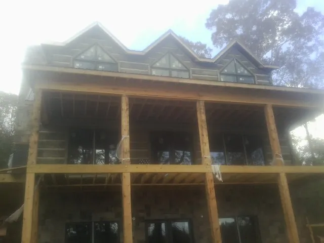 Dormers and porch framing on a large log home under construction — Roof Coating work by our crew in Glenfield