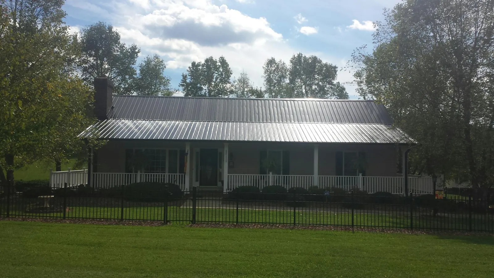 Gray metal roof on a brick ranch with a full width front porch — Gutter Guard Installation work by our crew in Glenfield