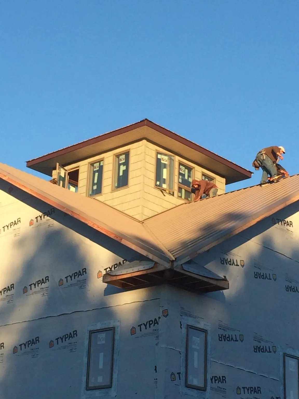 Roofers working around a rooftop cupola on a new metal roof at sunset — Roof Waterproofing in Glenfield by Roofing Brothers